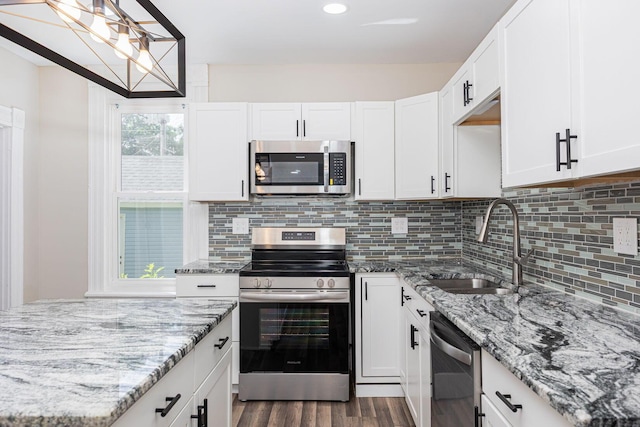 765 Campbell Ave, Columbus, OH 43222 - kitchen with appliances with stainless steel finishes, dark wood finished floors, light stone counters, tasteful backsplash, and white cabinetry
