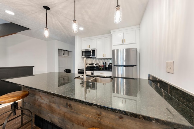 1768 Lake Meadow Dr Unit 1768H, Reynoldsburg, OH 43068 - kitchen featuring appliances with stainless steel finishes, white cabinetry, pendant lighting, dark stone countertops, and backsplash