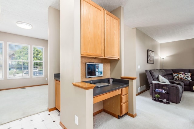 5899 Cove Point Ct, Columbus, OH 43228 - kitchen with dark countertops, open floor plan, built in desk, a textured ceiling, and light carpet