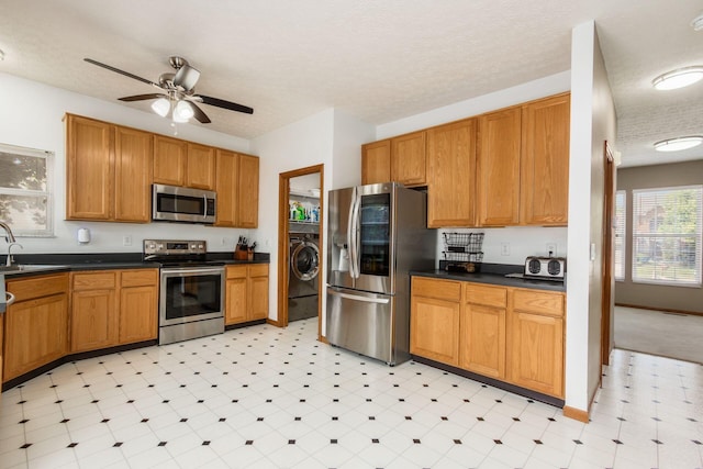 5899 Cove Point Ct, Columbus, OH 43228 - kitchen with stainless steel appliances, a textured ceiling, dark countertops, a ceiling fan, and washer / dryer