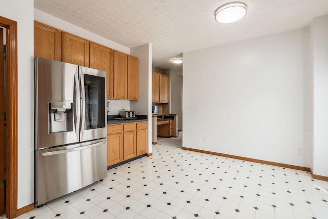 5899 Cove Point Ct, Columbus, OH 43228 - kitchen featuring stainless steel refrigerator with ice dispenser, light flooring, dark countertops, brown cabinets, and a textured ceiling