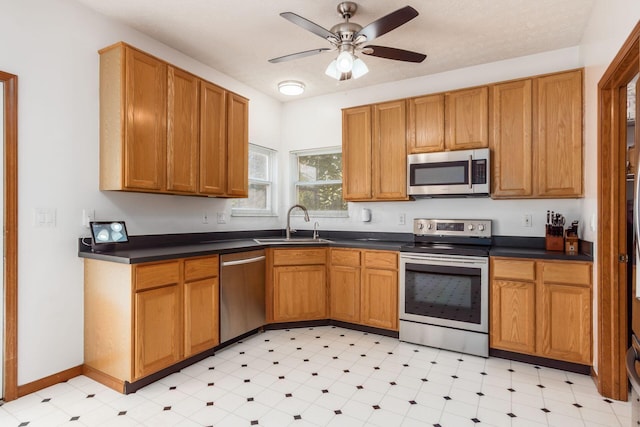 5899 Cove Point Ct, Columbus, OH 43228 - kitchen featuring appliances with stainless steel finishes, light floors, dark countertops, ceiling fan, and brown cabinetry