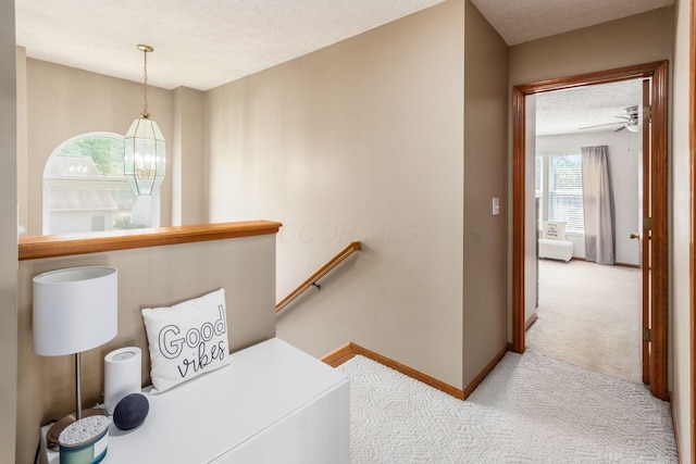5899 Cove Point Ct, Columbus, OH 43228 - hallway featuring carpet, an upstairs landing, a textured ceiling, and a chandelier