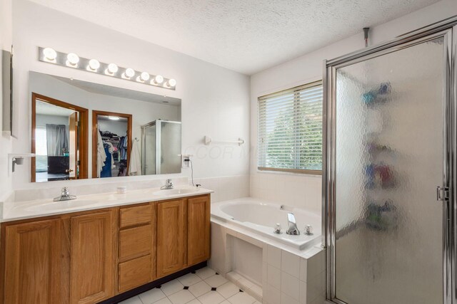 5899 Cove Point Ct, Columbus, OH 43228 - bathroom featuring a stall shower, a bath, double vanity, a walk in closet, and a textured ceiling