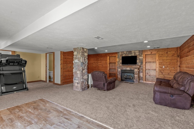 3582 Panhandle Rd, Delaware, OH 43015 - living room featuring a stone fireplace, carpet flooring, a textured ceiling, and wooden walls