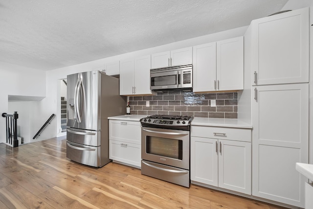 279 Old Coach Pl, Canal Winchester, OH 43110 - kitchen featuring appliances with stainless steel finishes, light countertops, a textured ceiling, white cabinetry, and tasteful backsplash
