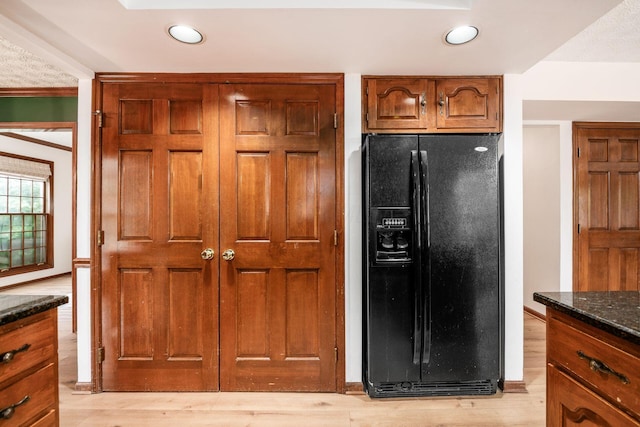 1169 Riva Ridge Blvd, Columbus, OH 43230 - kitchen with black fridge with ice dispenser, dark stone countertops, brown cabinetry, light wood-type flooring, and recessed lighting