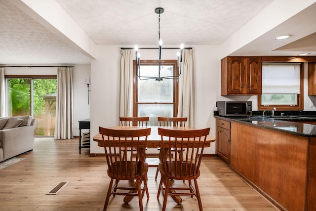 1169 Riva Ridge Blvd, Columbus, OH 43230 - dining space featuring a textured ceiling, light wood finished floors, and a chandelier