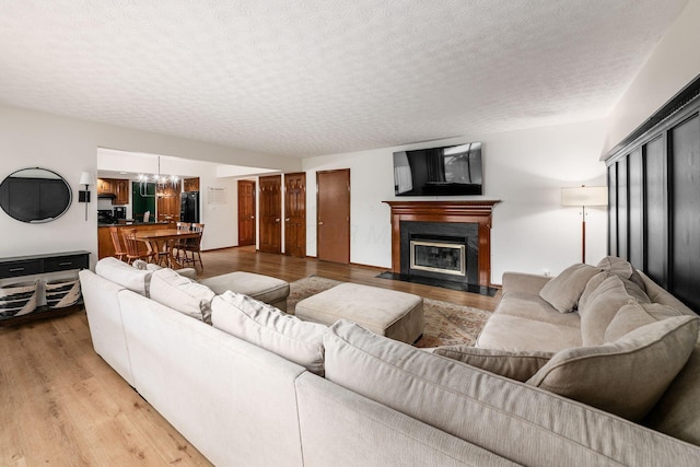 1169 Riva Ridge Blvd, Columbus, OH 43230 - living area featuring a textured ceiling, light wood-style flooring, a fireplace with flush hearth, and a chandelier