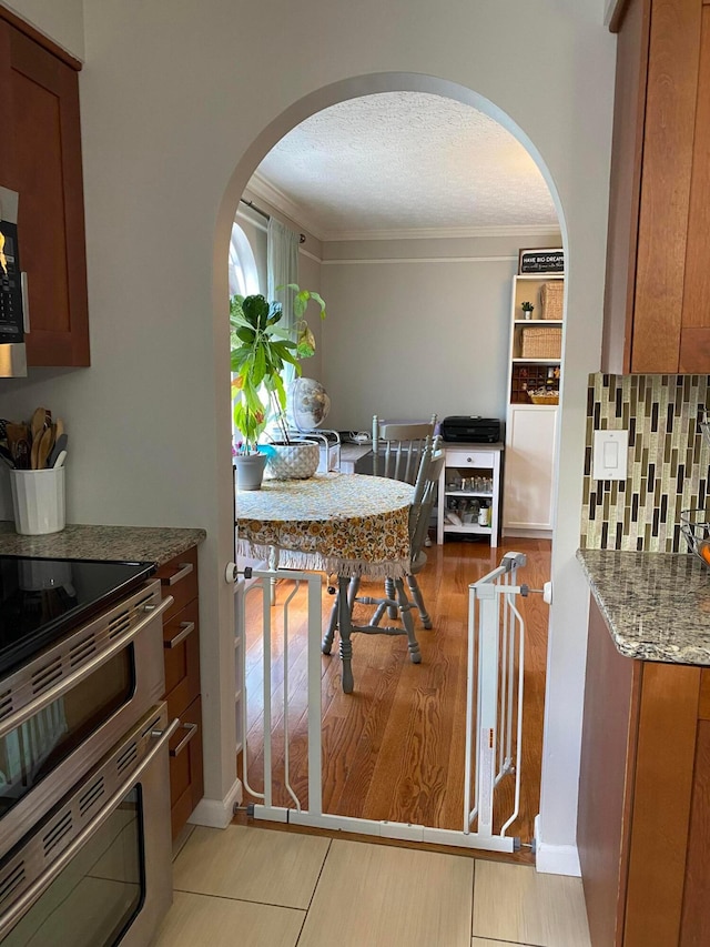 19 Ravine View Ct, Pataskala, OH 43062 - dining room featuring arched walkways, light wood-type flooring, crown molding, and a textured ceiling