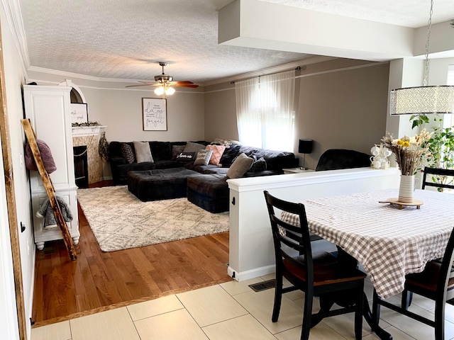 19 Ravine View Ct, Pataskala, OH 43062 - dining area featuring ceiling fan, a premium fireplace, crown molding, and a textured ceiling