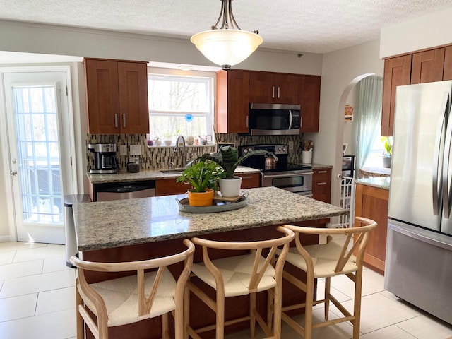 19 Ravine View Ct, Pataskala, OH 43062 - kitchen with appliances with stainless steel finishes, light tile patterned flooring, decorative backsplash, arched walkways, and a textured ceiling