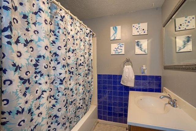 124 Wyandotte St, Lancaster, OH 43130 - bathroom featuring tile walls, a textured ceiling, vanity, shower / bath combo with shower curtain, and a wainscoted wall