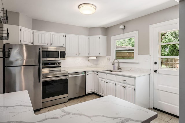 2486 Cranford Rd, Columbus, OH 43221 - kitchen with appliances with stainless steel finishes, light stone countertops, light tile patterned floors, and white cabinets