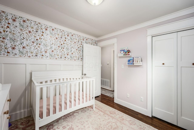 2486 Cranford Rd, Columbus, OH 43221 - bedroom featuring ornamental molding, a wainscoted wall, dark wood finished floors, a closet, and a crib