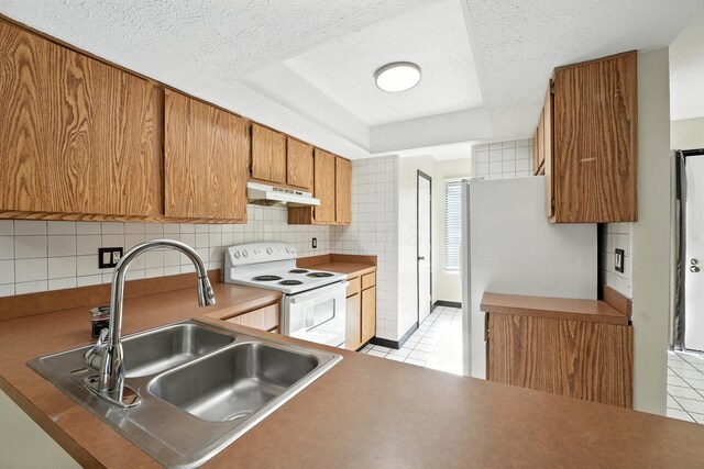 2663 Cedar Lake Dr, Dublin, OH 43016 - kitchen featuring white electric range, under cabinet range hood, light tile patterned floors, brown cabinetry, and backsplash