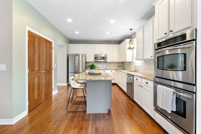 7125 Marrisey Loop, Galena, OH 43021 - kitchen with appliances with stainless steel finishes, a kitchen island, decorative backsplash, white cabinetry, and recessed lighting