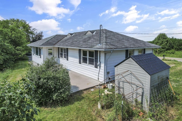 7688 State Route 257, Prospect, OH 43342 - rear view of house featuring a shingled roof, a storage unit, and a lawn