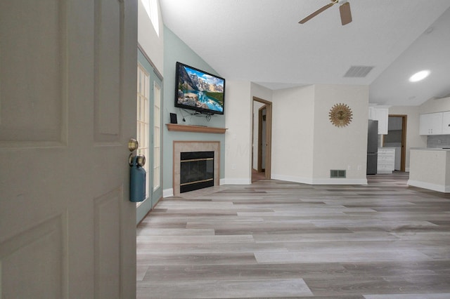 3712 E Links Cir, Hilliard, OH 43026 - unfurnished living room featuring lofted ceiling, a ceiling fan, light wood finished floors, and a tiled fireplace
