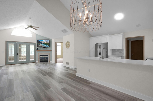 3712 E Links Cir, Hilliard, OH 43026 - unfurnished living room featuring a ceiling fan, vaulted ceiling, wood finished floors, a fireplace, and a chandelier