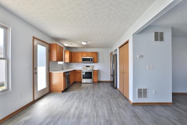 1852 Meadowlawn Dr, Columbus, OH 43219 - kitchen featuring stainless steel appliances, light wood-style flooring, light countertops, healthy amount of natural light, and a textured ceiling