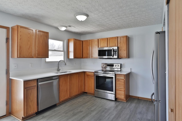 1852 Meadowlawn Dr, Columbus, OH 43219 - kitchen featuring appliances with stainless steel finishes, light wood finished floors, light countertops, brown cabinetry, and a textured ceiling