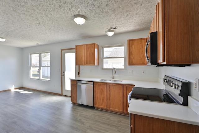 1852 Meadowlawn Dr, Columbus, OH 43219 - kitchen with appliances with stainless steel finishes, plenty of natural light, brown cabinets, and a textured ceiling