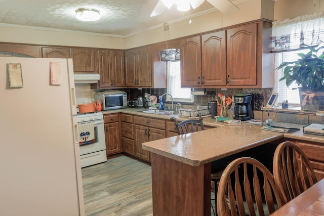 72 S Oakley Ave, Columbus, OH 43204 - kitchen with white appliances, under cabinet range hood, a peninsula, decorative backsplash, and ornamental molding