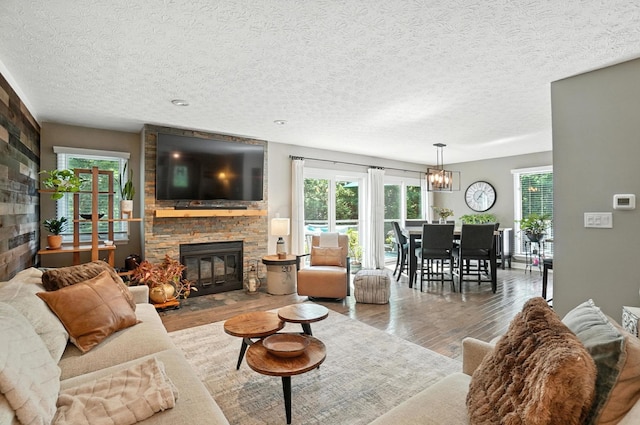 96 Executive Ct Unit B, Westerville, OH 43081 - living room featuring wood finished floors, a fireplace, a chandelier, plenty of natural light, and a textured ceiling