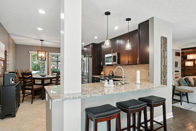 96 Executive Ct Unit B, Westerville, OH 43081 - kitchen with appliances with stainless steel finishes, backsplash, light stone countertops, a peninsula, and a breakfast bar