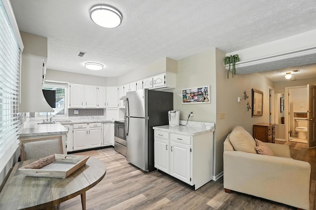 96 Executive Ct Unit B, Westerville, OH 43081 - kitchen with stainless steel appliances, light wood-style floors, white cabinetry, a textured ceiling, and open floor plan