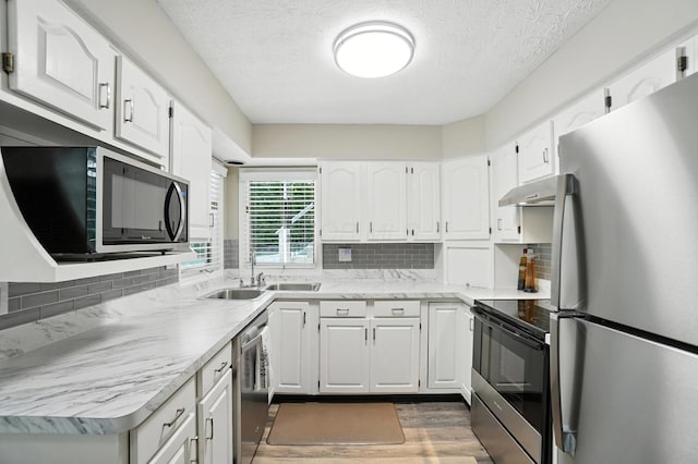 96 Executive Ct Unit B, Westerville, OH 43081 - kitchen featuring appliances with stainless steel finishes, under cabinet range hood, decorative backsplash, wood finished floors, and a textured ceiling