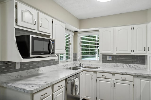 96 Executive Ct Unit B, Westerville, OH 43081 - kitchen with stainless steel dishwasher, backsplash, white cabinetry, light countertops, and a textured ceiling