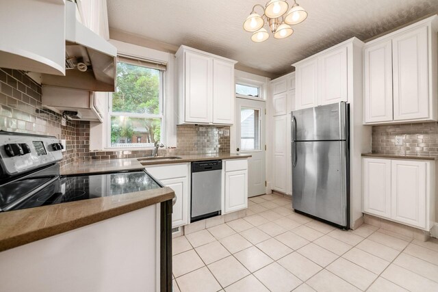 675-677 Beech St, Columbus, OH 43206 - kitchen featuring stainless steel appliances, tasteful backsplash, white cabinetry, a chandelier, and light tile patterned floors