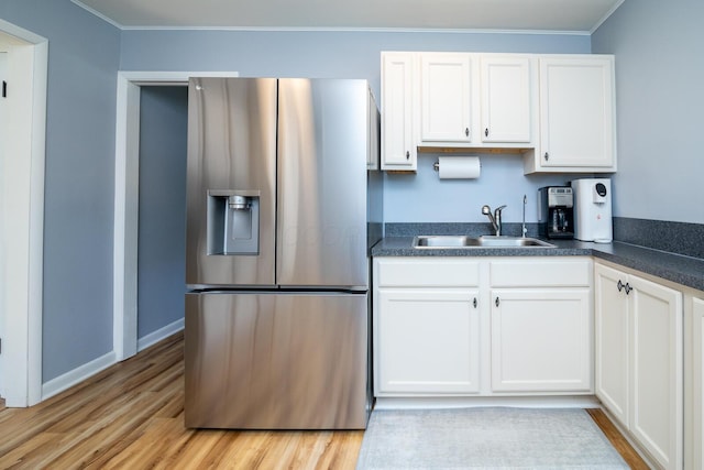 922 Afton Rd, Columbus, OH 43221 - kitchen featuring stainless steel fridge with ice dispenser, dark countertops, white cabinets, light wood-style flooring, and ornamental molding