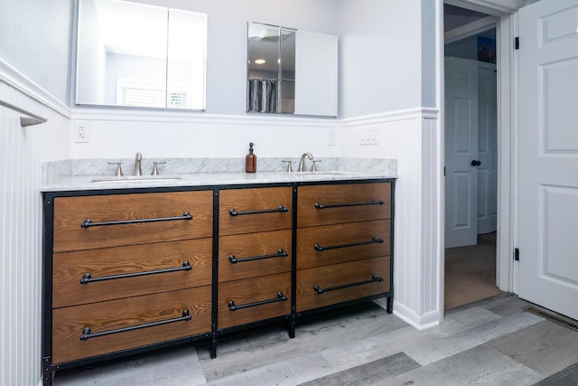 922 Afton Rd, Columbus, OH 43221 - full bath featuring wood finished floors, double vanity, and a wainscoted wall