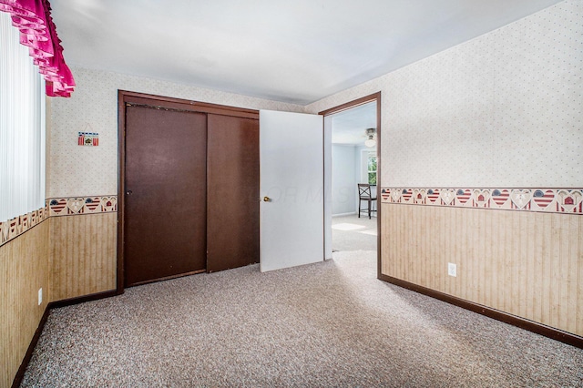 2883 Tucker Rd, Lucas, OH 44843 - unfurnished bedroom featuring wallpapered walls, wainscoting, carpet floors, wood walls, and a closet