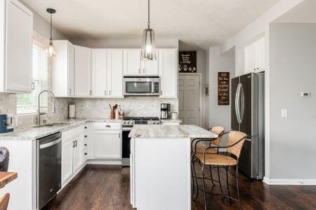 1883 Caplinger Dr, Grove City, OH 43123 - kitchen with appliances with stainless steel finishes, a center island, a breakfast bar, and tasteful backsplash