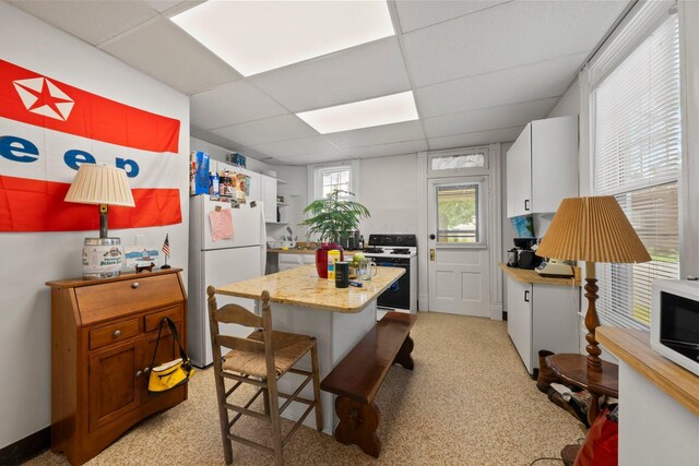 1561 Glenn Ave, Columbus, OH 43212 - kitchen featuring white appliances, a paneled ceiling, a kitchen island, a kitchen bar, and light carpet