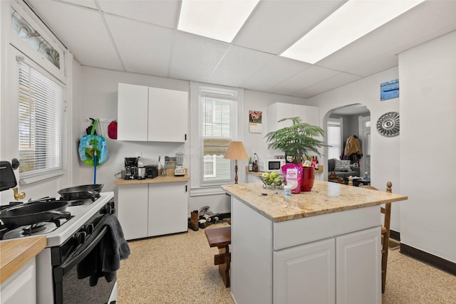 1561 Glenn Ave, Columbus, OH 43212 - kitchen with gas stove, arched walkways, light countertops, white cabinets, and a drop ceiling