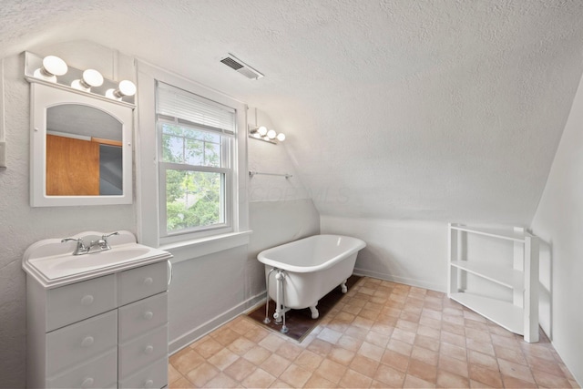 1561 Glenn Ave, Columbus, OH 43212 - bathroom with a textured ceiling, a freestanding tub, vanity, and vaulted ceiling