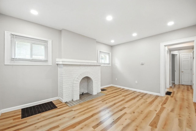 87 N Warren Ave, Columbus, OH 43204 - unfurnished living room with wood finished floors, a brick fireplace, and recessed lighting