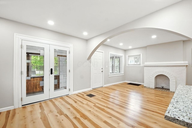 87 N Warren Ave, Columbus, OH 43204 - unfurnished living room featuring arched walkways, wood finished floors, plenty of natural light, french doors, and recessed lighting