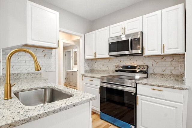 87 N Warren Ave, Columbus, OH 43204 - kitchen with stainless steel appliances, decorative backsplash, white cabinetry, and light stone counters