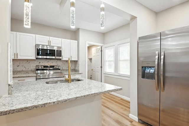 87 N Warren Ave, Columbus, OH 43204 - kitchen featuring appliances with stainless steel finishes, white cabinetry, tasteful backsplash, light wood-style floors, and light stone counters