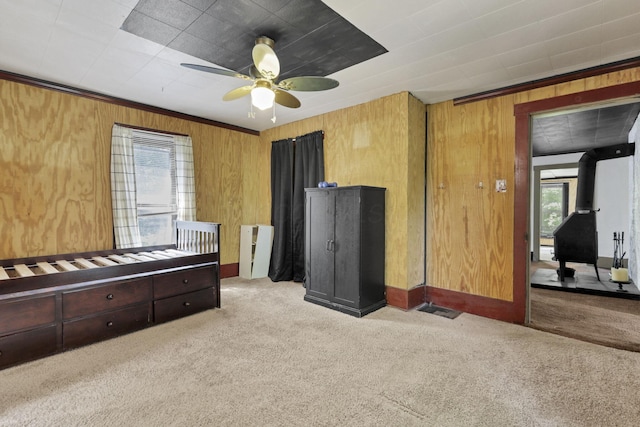 27380 Miller Rd, Rockbridge, OH 43149 - bedroom featuring carpet flooring, wooden walls, a ceiling fan, ornamental molding, and a wood stove