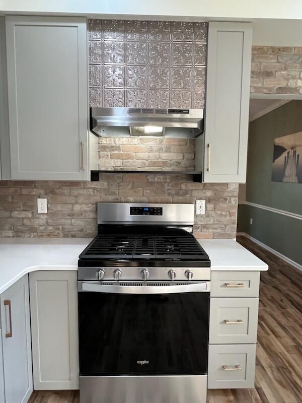 450 Village Ridge Ct, Powell, OH 43065 - kitchen with gas range, exhaust hood, tasteful backsplash, and wood finished floors