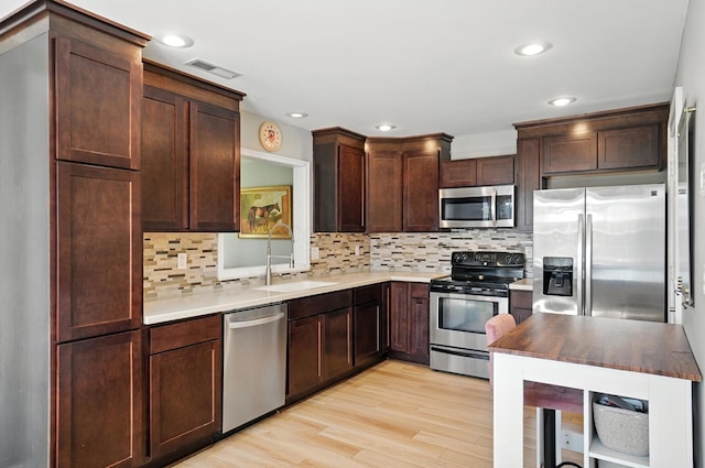 1817 Ibson Dr, Powell, OH 43065 - kitchen featuring appliances with stainless steel finishes, light wood-style floors, dark brown cabinetry, decorative backsplash, and recessed lighting