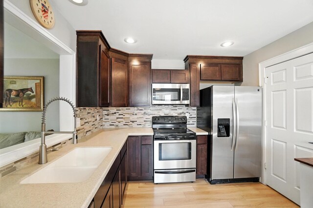 1817 Ibson Dr, Powell, OH 43065 - kitchen featuring appliances with stainless steel finishes, dark brown cabinets, backsplash, light wood-type flooring, and recessed lighting