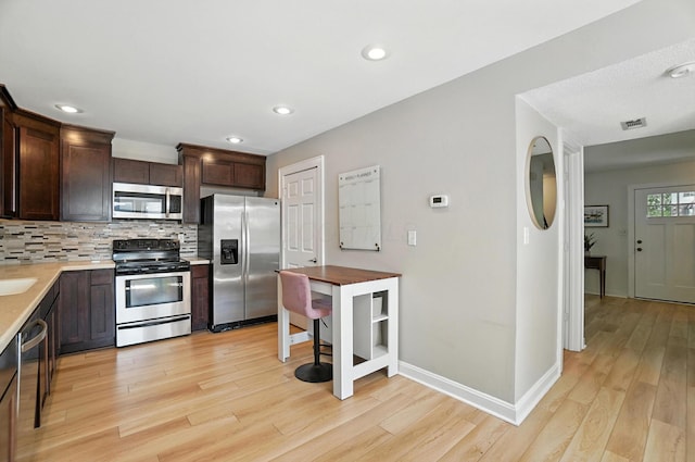 1817 Ibson Dr, Powell, OH 43065 - kitchen featuring stainless steel appliances, dark brown cabinetry, light wood-style flooring, light countertops, and recessed lighting